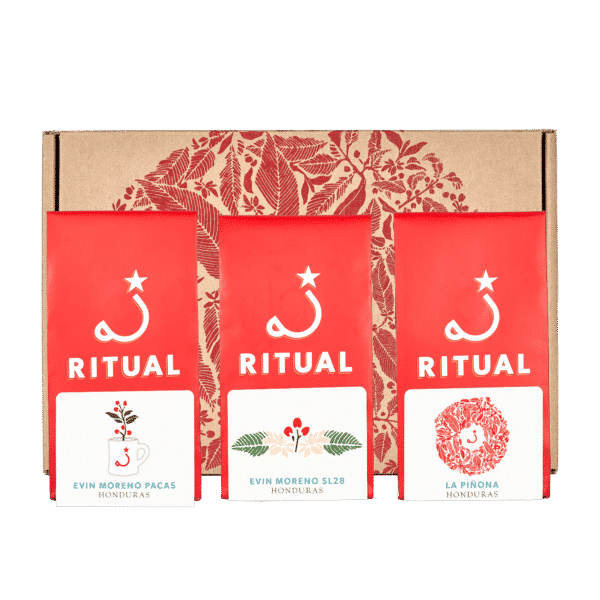 Three 4 ounce bags of coffee with a cardboard box decorated with a red wreath