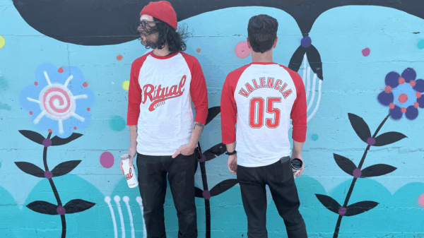 Models wearing Ritual baseball tee in front of mural