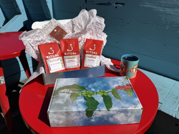 Three 10 ounce bags of coffee in a box on a red table