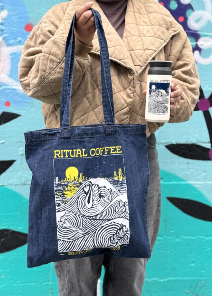 Person holding latte wave tote bag and tumbler