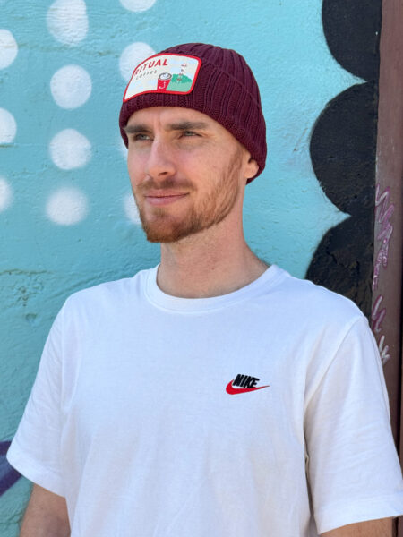 Model wearing cable beanie with a designed embroidered patch.