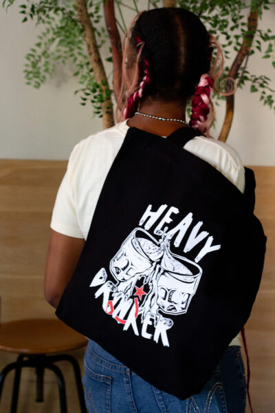 Person wearing black tote bag that says "heavy drinker"