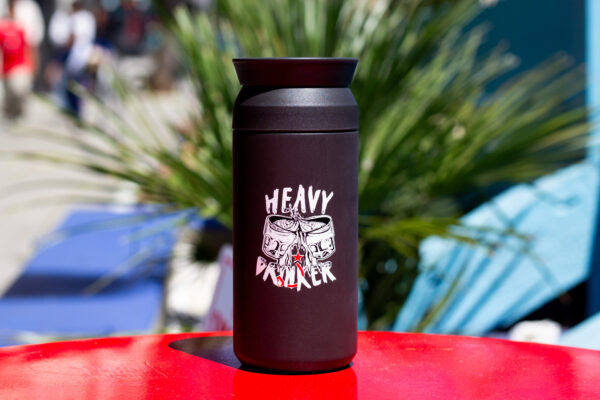 A black tumbler that says "heavy drinker" on a red table
