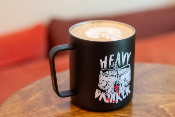 A black camp mug that says "heavy drinker" on a wooden table